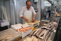 Spain, Andalucia, Cadiz, A fishmonger fillets fish at his stall in the Central Market.