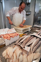 Spain, Andalucia, Cadiz, A fishmonger fillets fish at his stall in the Central Market.