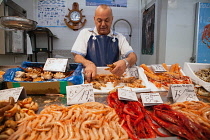 Spain, Andalucia, Cadiz, A fishmonger prepares an order for langoustines at his stall in the Central Market.