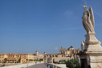 Spain, Andalucia, Cordoba, statue of San Rafael patron saint of Cordoba on the Roman Bridge with the Mezquita Cathedral in the background.
