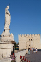 Spain, Andalucia, Cordoba, Statue of San Rafael patron saint of Cordoba on the Roman Bridge with the Torreo de la Calahorra in the background.
