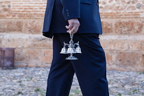 Spain, Andalucia, Granada, A man holds the cluster of small bells that are rung during the Corpus Christi procession.
