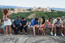 Spain, Andalucia, Granada, Tourists look across to the Alhambra from the viewpoint at Iglesia de San Nicolas in the Albayzin district.