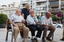 Spain, Andalucia, Granada, A group of men enjoying an evening get-together on a bench in Puerta Real.