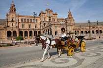 Spain, Andalucia, Seville, Plaza de Espana with horse-drawn carriage taking tourists for a ride in the foreground.