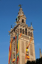 Spain, Andalucia, Seville, The Giralda of Seville Cathedral with banners and streamers hanging from the bell  tower to celebrate the feast of Corpus Christi.