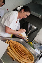 Spain, Andalucia, Seville, A cook prepares a helping of churros.