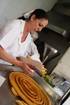 Spain, Andalucia, Seville, A cook prepares a helping of churros.