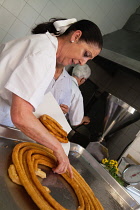 Spain, Andalucia, Seville, A cook prepares a helping of churros.