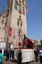 Spain, Andalucia, Seville, A procession as part of the Corpus Christi festival about to enter the cathedral with the Giralda in the background.