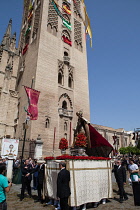 Spain, Andalucia, Seville, A procession as part of the Corpus Christi festival about to enter the cathedral with the Giralda in the background.