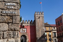 Spain, Andalucia, Seville, Gate and portal to the entrance of the Alcazar with the street sign for Plaza del Triunfo in the foreground to the left.