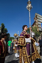 Spain, Andalucia, Seville, An altar server leads the Corpus Chrisit procession from Iglesia de la Magdelena .