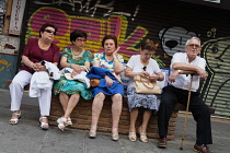 Spain, Andalucia, Seville, Triana residents wile away the evening on a bench on Calle San Jacinto .