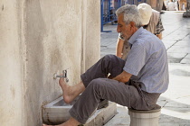 Turkey, Istanbul, Muslim man washing his feet at the New Mosque, Eminonu Yeni Camii, Eminonu.