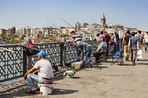 Turkey, Istanbul, Men fishing on Galata Bridge, Galata Tower in background.