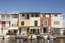 France, Port Grimaud, Boats moored in front of waterfront homes.