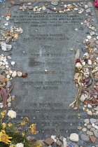 Germany, Lower Saxony, Bergen Belsen, Memorial plaque within the grounds of the Concentration Camp, with pebbles and flowers left as tributes.