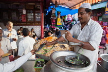 India, Delhi, A muslim cook prepares to weigh a serving of rice biryani in the old city of Delhi.