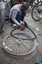 India, Delhi, A road-side bicycle repairman, puncture wallah, mending a puncture.
