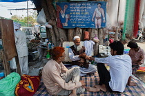 India, Delhi, Road-side medical practitioner treats a patient in the old quarter of Delhi.