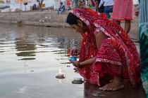India, Rajasthan, Pushkar, A pilgrim puts a floating flame onto Pushkar lake.