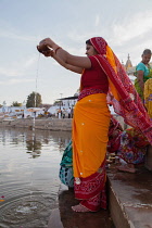 India, Rajasthan, Pushkar, A pilgrim pours water into Pushkar lake .