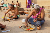 India, Uttar Pradesh, Varanasi, Male members from a bereaved family perform puja on the ghats beside the Ganges in Varanasi.