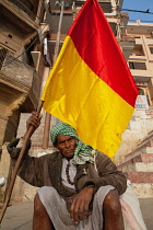 India, Uttar Pradesh, Varanasi, A flag-bearing pilgrim on the ghats at Varanasi.