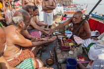 India, Uttar Pradesh, Varanasi, A bereaved family perform puja on the ghats at Varanasi after the cremation of a deceased relative.