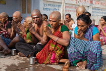India, Uttar Pradesh, Varanasi, A bereaved family perform puja on the ghats at Varanasi after the cremation of a deceased relative .