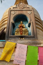 India, Bihar, Bodhgaya, An statue of the Buddha set in a stupa with prayer flags at the base at the Mahabodhi Temple in Bodhgaya.