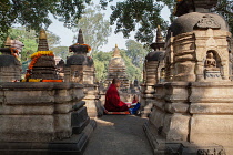 India, Bihar, Bodhgaya, Monk praying between stuapas at the Mahabodhi Temple in Bodhgaya.