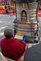 India, Bihar, Bodhgaya, Monk praying before a statue of the Buddha set in a stupa at the Mahabodhi Temple in Bodhgaya.