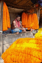 India, Bengal, Kolkata, Vendor selling garlands of marigolds in Malik Ghat Flower Market in Kolkata.