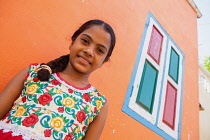 India, Tamil Nadu, Mahabalipuram, Portrait of a Tamil girl standing outside her orange painted home in Mahabalipuram.
