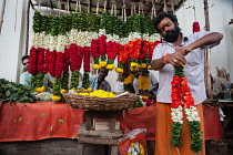 India, Andhra Pradesh, Tirupati, Flower vendor making garlands.