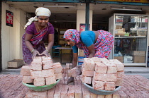 India, Telengana, Hyderabad, Female labourers loading bricks onto trays.
