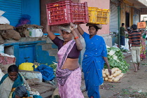 India, Telengana, Secunderabad, Women porters carrying crates of tomatoes on their heads in the vegetable market in Secunderabad.