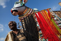 India, Tamil Nadu, Madurai, A man selling religious cords & threads in front of a statue of Nandi .
