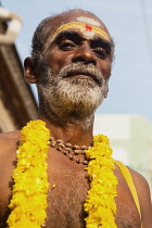 India, Tamil Nadu, Madurai, Portrait of a pilgrim wearing a garland of marigolds at the Sri Meenakshi Temple in Madurai.
