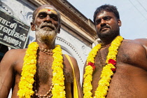 India, Tamil Nadu, Madurai, Portrait of pilgrims wearing garlands of marigolds at the Sri Meenakshi Temple in Madurai.