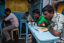 India, Tamil Nadu, Madurai, Men eating rice biryani at a food shack in Madurai.