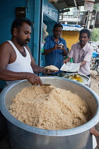 India, Tamil Nadu, Madurai, Cook serving portions of rice biryani at a food shack in Madurai.