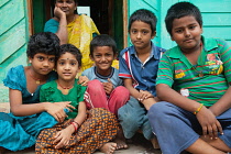 India, Tamil Nadu, Melur, Brothers & sisters with their mother in the background sit outside their family home in Melur.