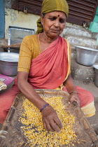 India, Tamil Nadu, Tiruchirappalli, Trichy, Woman winnowing maize in the market at Trichy.