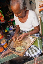 India, Tamil Nadu, Tiruchirappalli, Trichy, Making making beedis to sell in his market booth in Trichy.