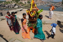 India, Karnataka, Hampi, Pilgrims pass by a chariot on the banks of theTungabhadra River at Hampi.