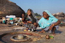 India, Karnataka, Hampi, Pilgrims make an offering at a lingam beside the Tungabhadra River in Hampi.