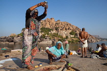 India, Karnataka, Hampi, Pilgrims make an offering at a lingam beside the Tungabhadra River in Hampi.